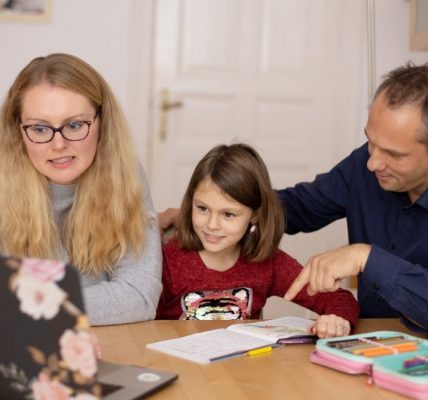 A family is engaged in homeschooling, using technology to learn together in a cozy home setting.