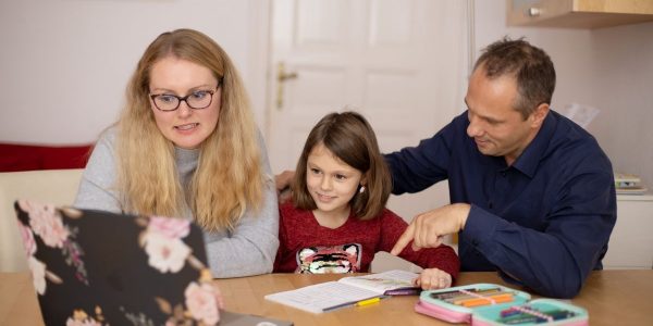 A family is engaged in homeschooling, using technology to learn together in a cozy home setting.
